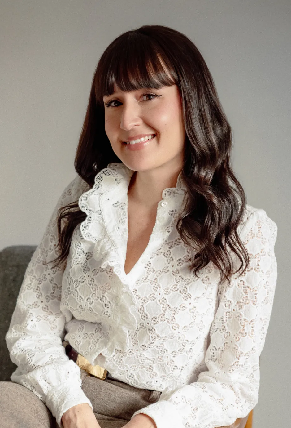 Dr. Ileana Hernandez, chronic pain and illness therapist, smiling in a wooden armchair